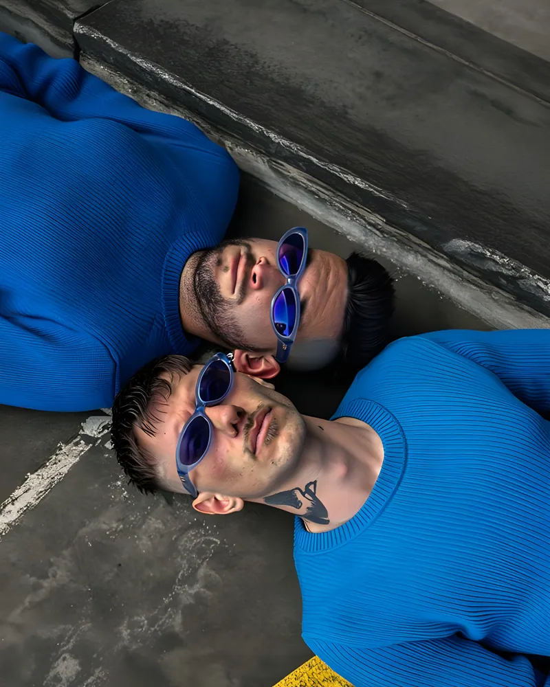 El dúo acostado en el piso con lentes azules, visto desde arriba